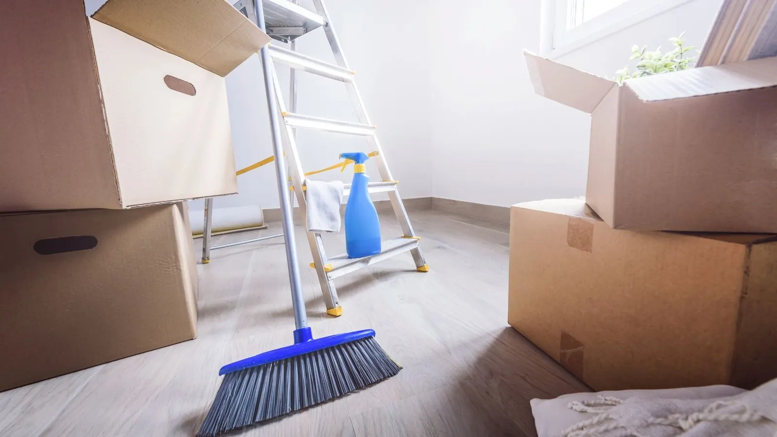 Moving boxes and broom during move-out cleaning preparation