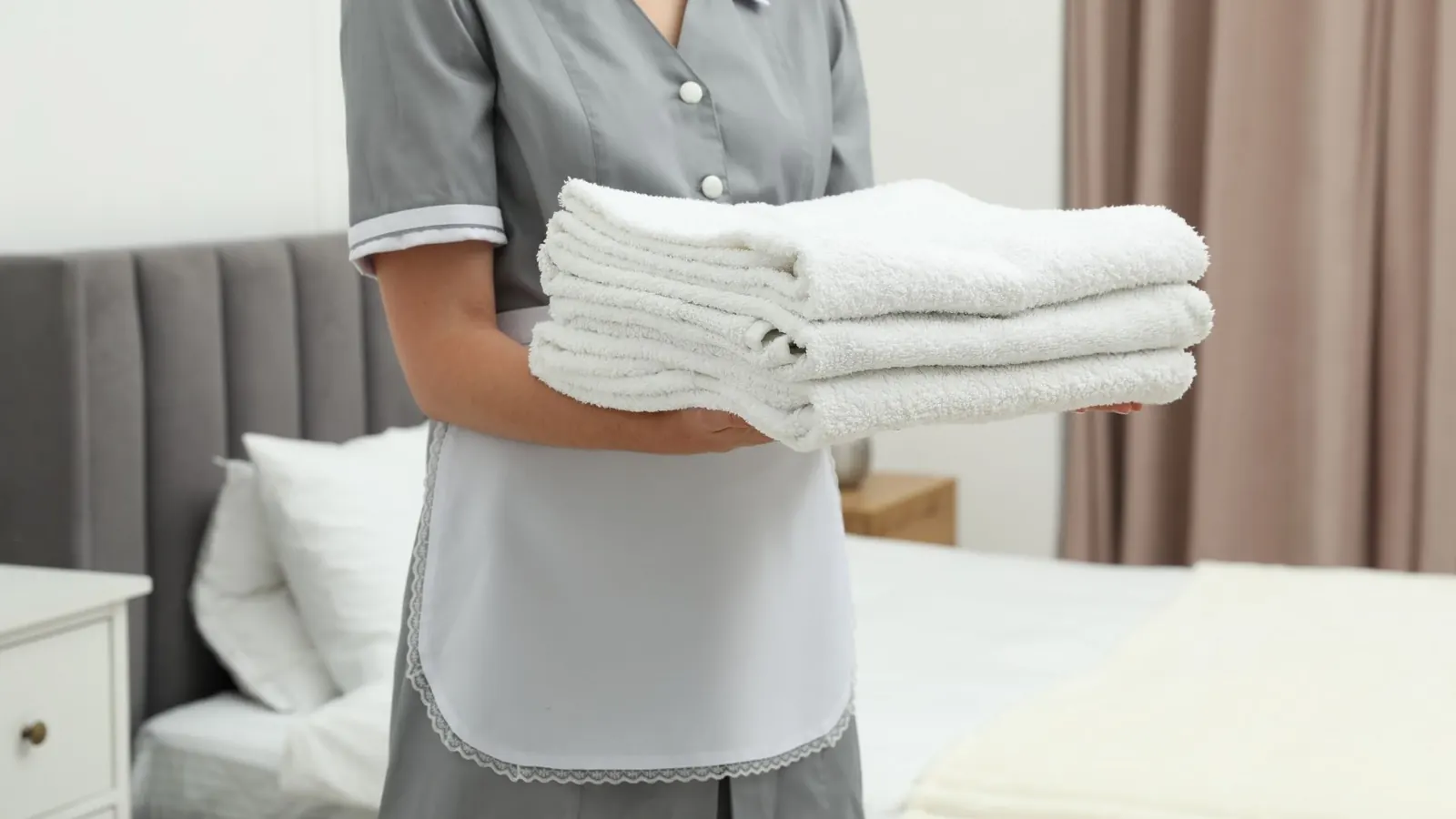 Housekeeper holding fresh towels as part of maid service preparation